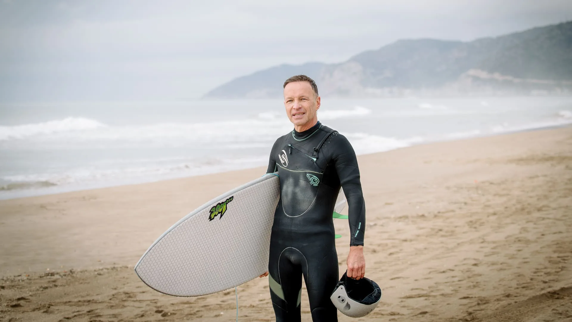 265 días sin olas: un surfista con neopreno y su tabla en una playa del Mediterráneo