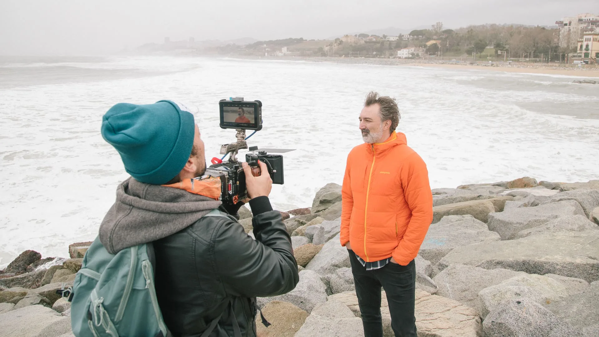 Rodaje de 265 días sin olas: un operador entrevista a un hombre en las rocas frente al mar revuelto