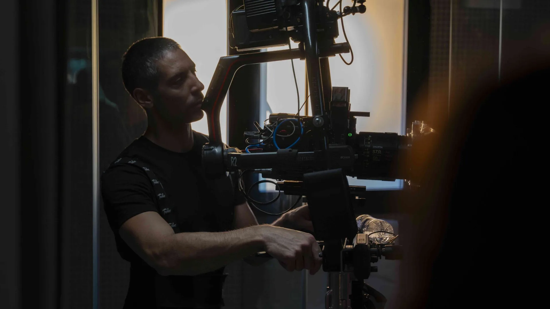Rodaje de Activia: el operador prepara un plano con un Ronin, a contraluz de una ventana