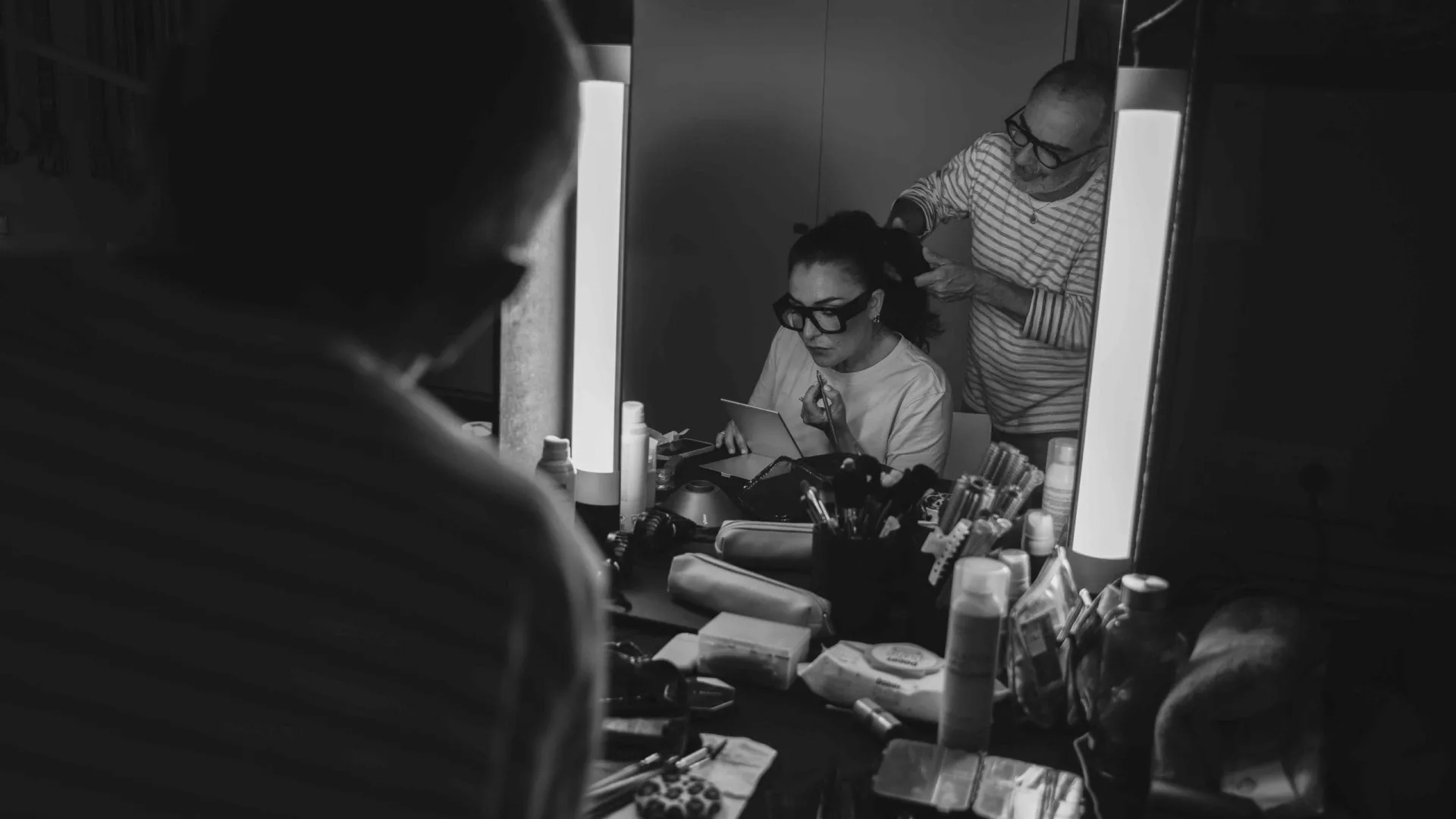 Rodaje de Activia: la actriz en peluquería y maquillaje, vista en un espejo iluminado, en blanco y negro