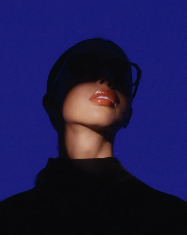 Mujer con gafas oscuras y labios brillantes sobre fondo azul intenso, de Ch.Martinez