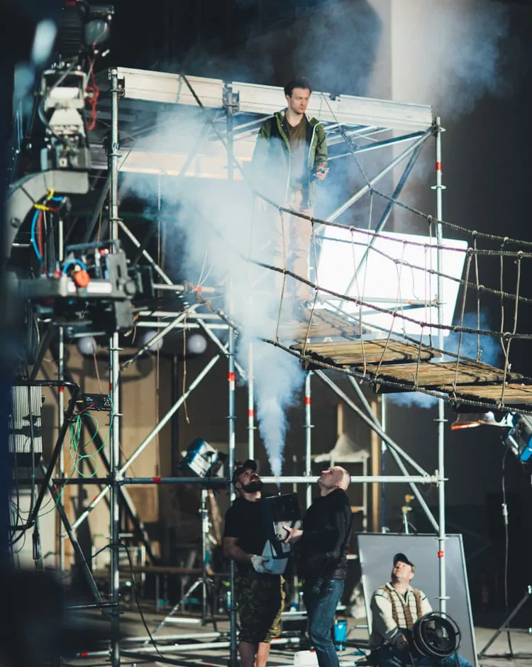 Behind the scenes of a commercial by Ene Fariña: an actor on a scaffold rope bridge amid smoke