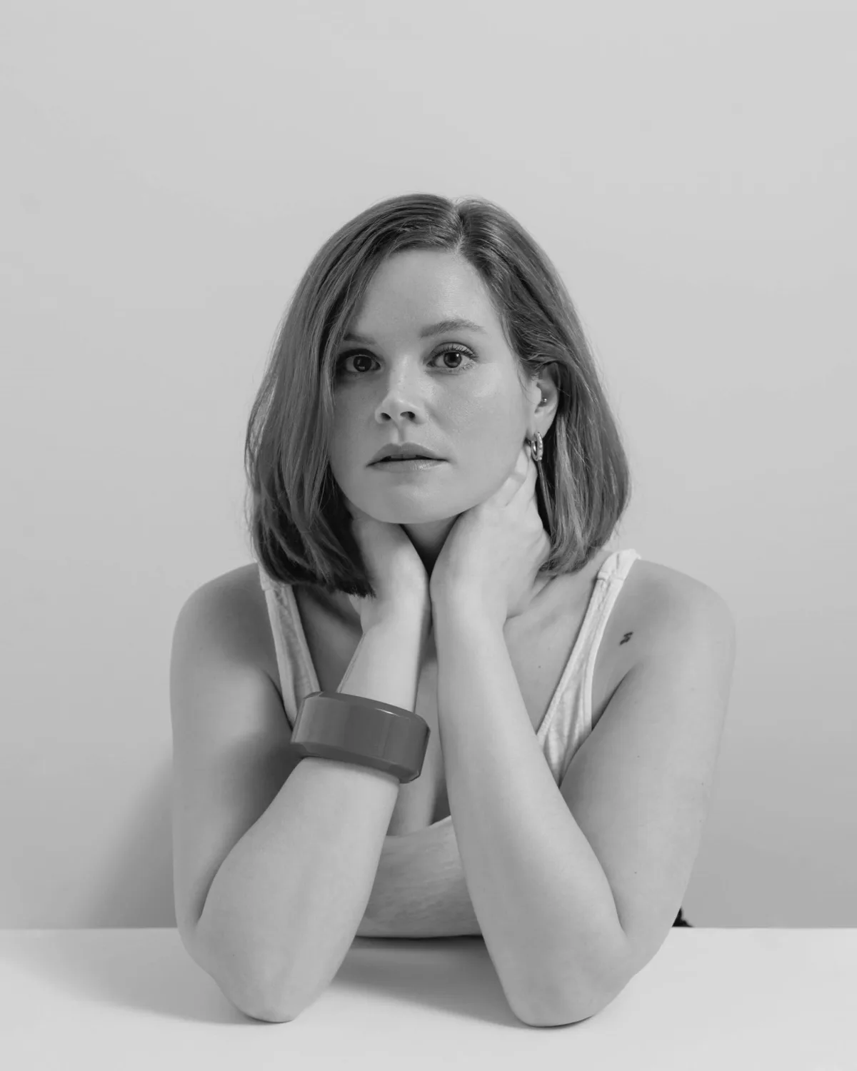 Retrato de estudio en blanco y negro de una mujer con la barbilla entre las manos