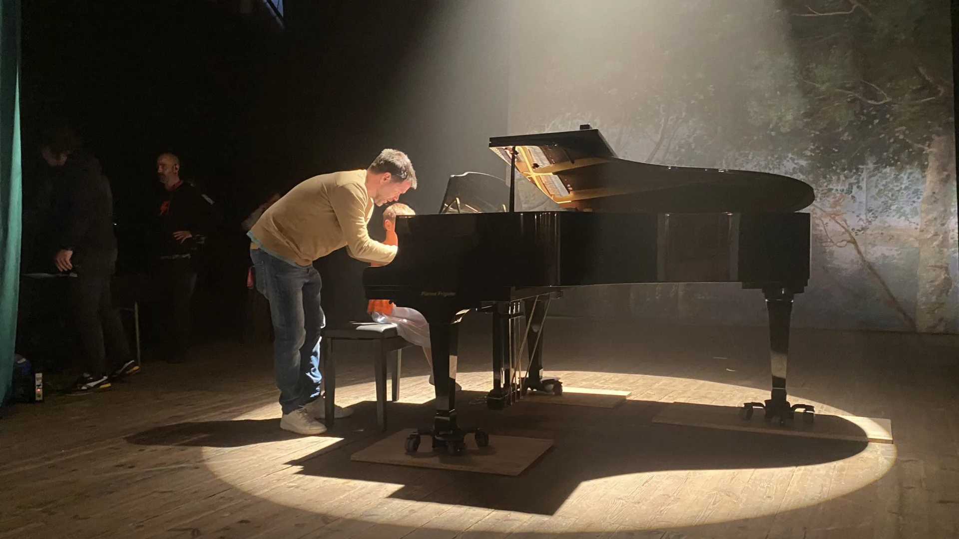 Rodaje para la Fundación Josep Carreras: un técnico ajusta el piano de cola bajo un foco en el escenario