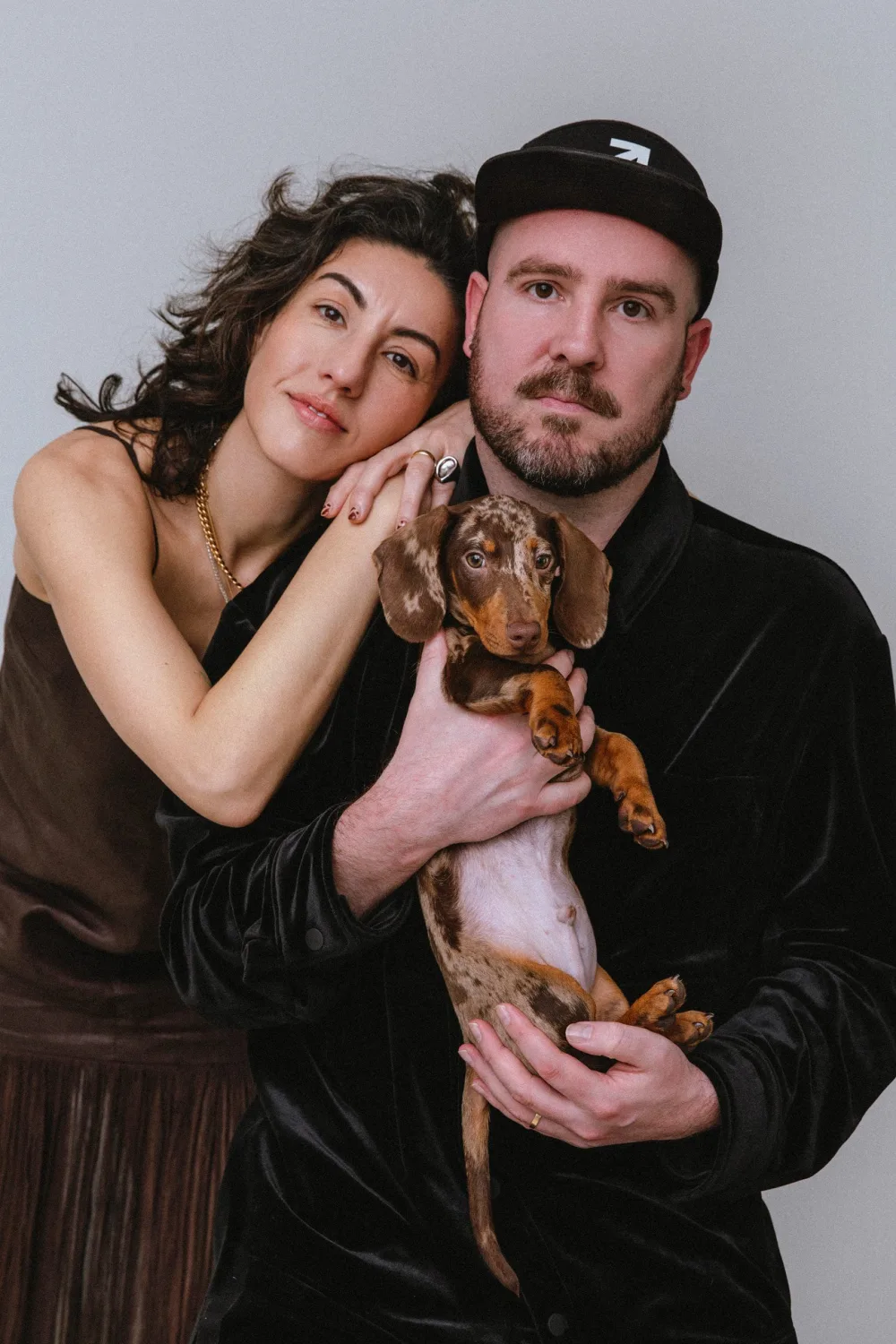 Retrato de estudio de un hombre y una mujer con un cachorro de teckel, de la página de HumAIn