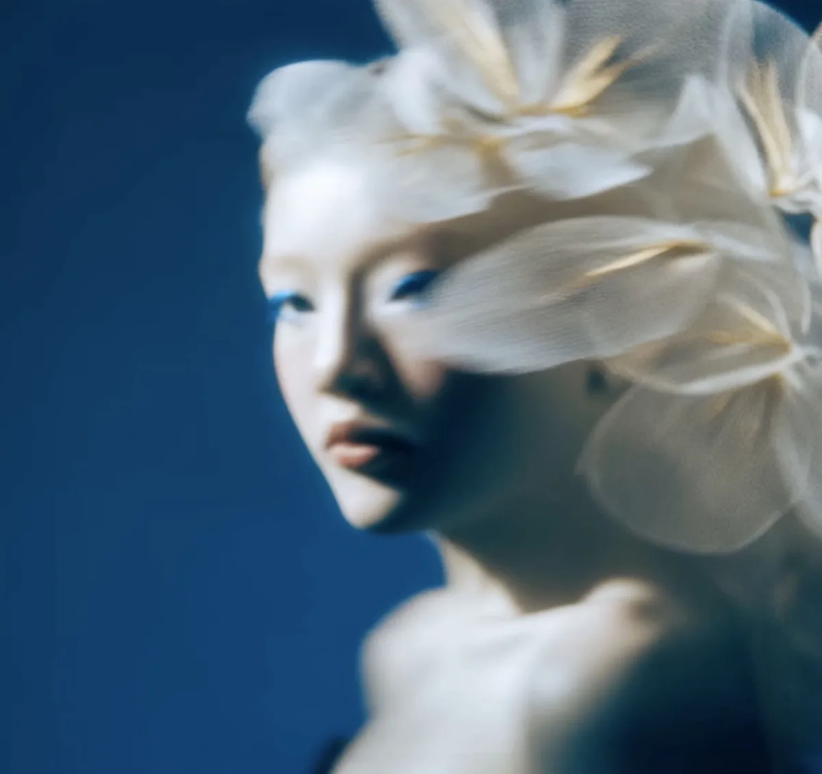 Retrato con IA de una mujer pálida con pétalos blancos translúcidos en el pelo, del trabajo de HumAIn