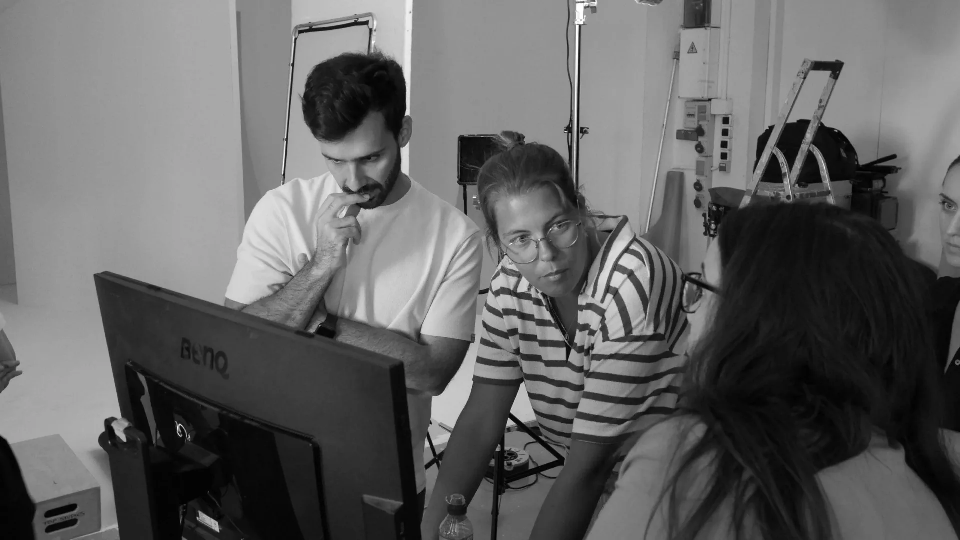 Rodaje de ISDIN Acniben: equipo comentando una toma alrededor de un monitor, en blanco y negro