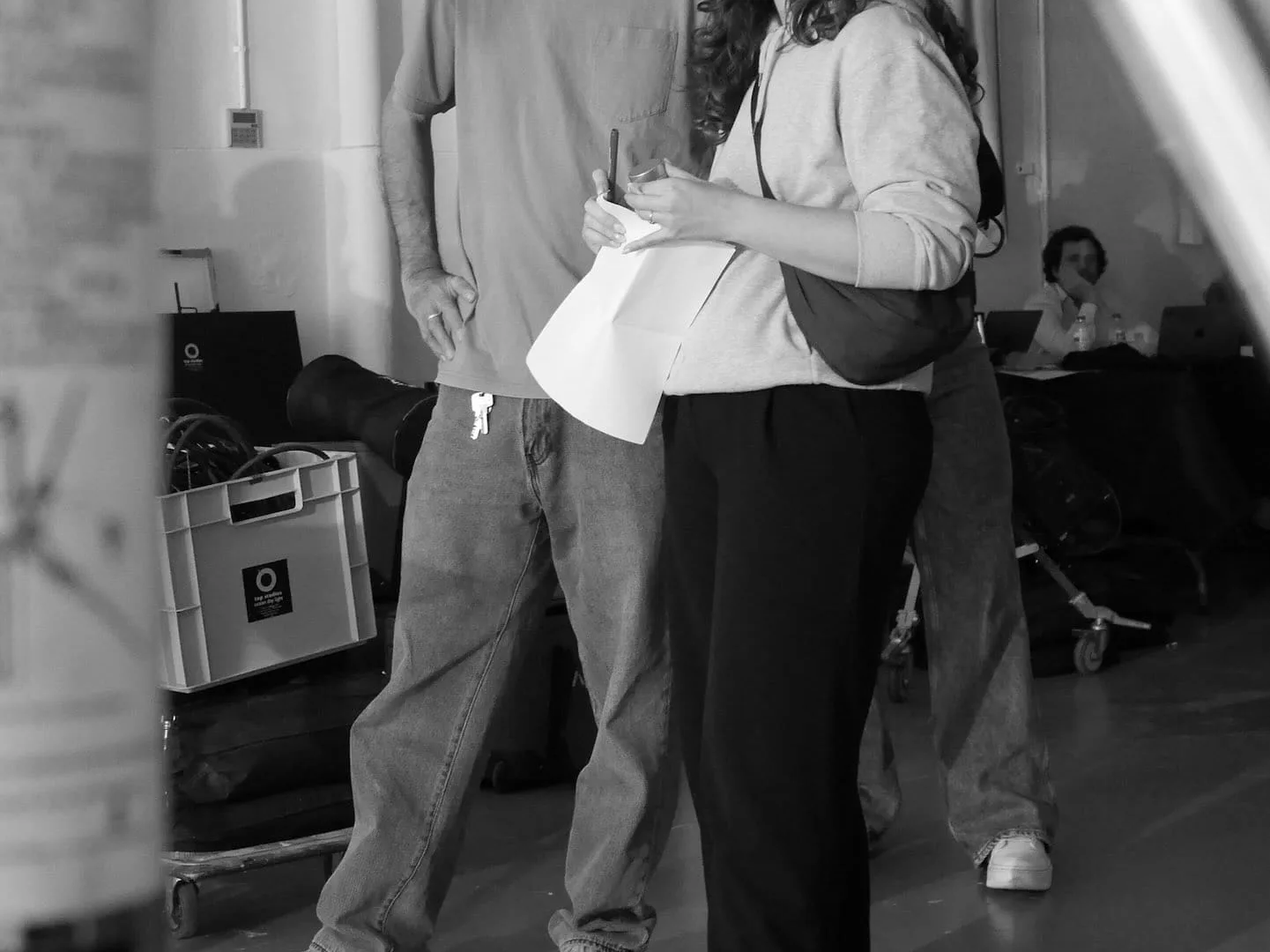 Isdin Hyaluronic making of: two crew members watching the set with papers in hand, black and white