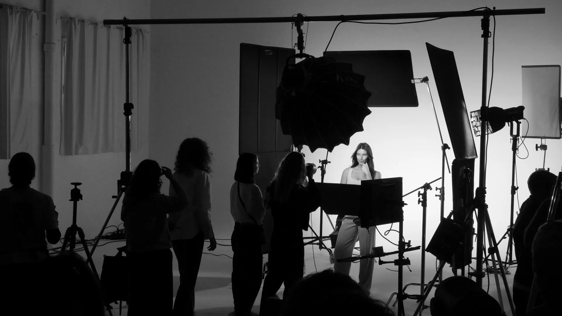 Isdin Hyaluronic making of: the crew watches the model pose under the studio lights, black and white