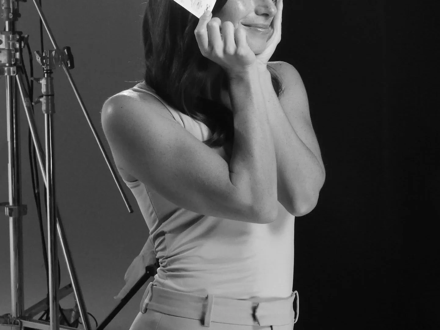 Isdin Hyaluronic shoot: smiling model holding a product sachet to her cheek under studio lights