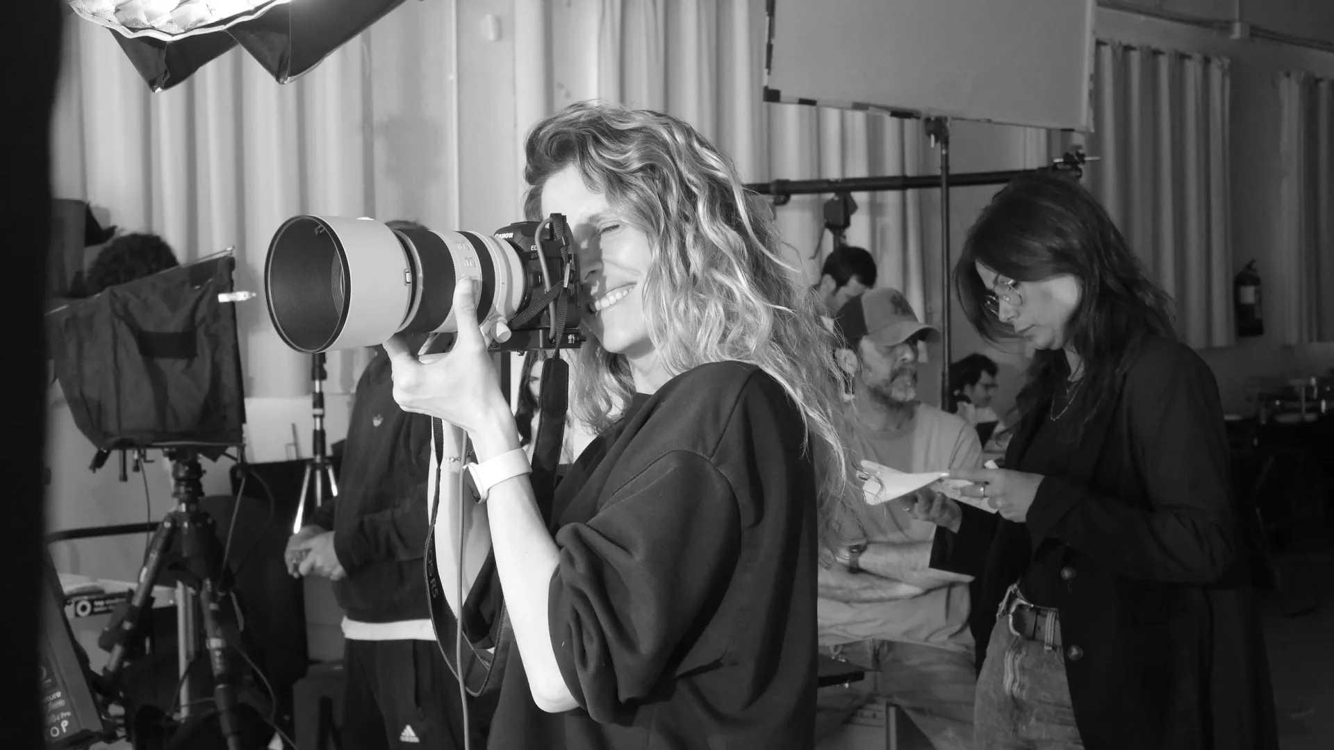 Isdin Hyaluronic making of: photographer with a telephoto lens smiling on set, black and white