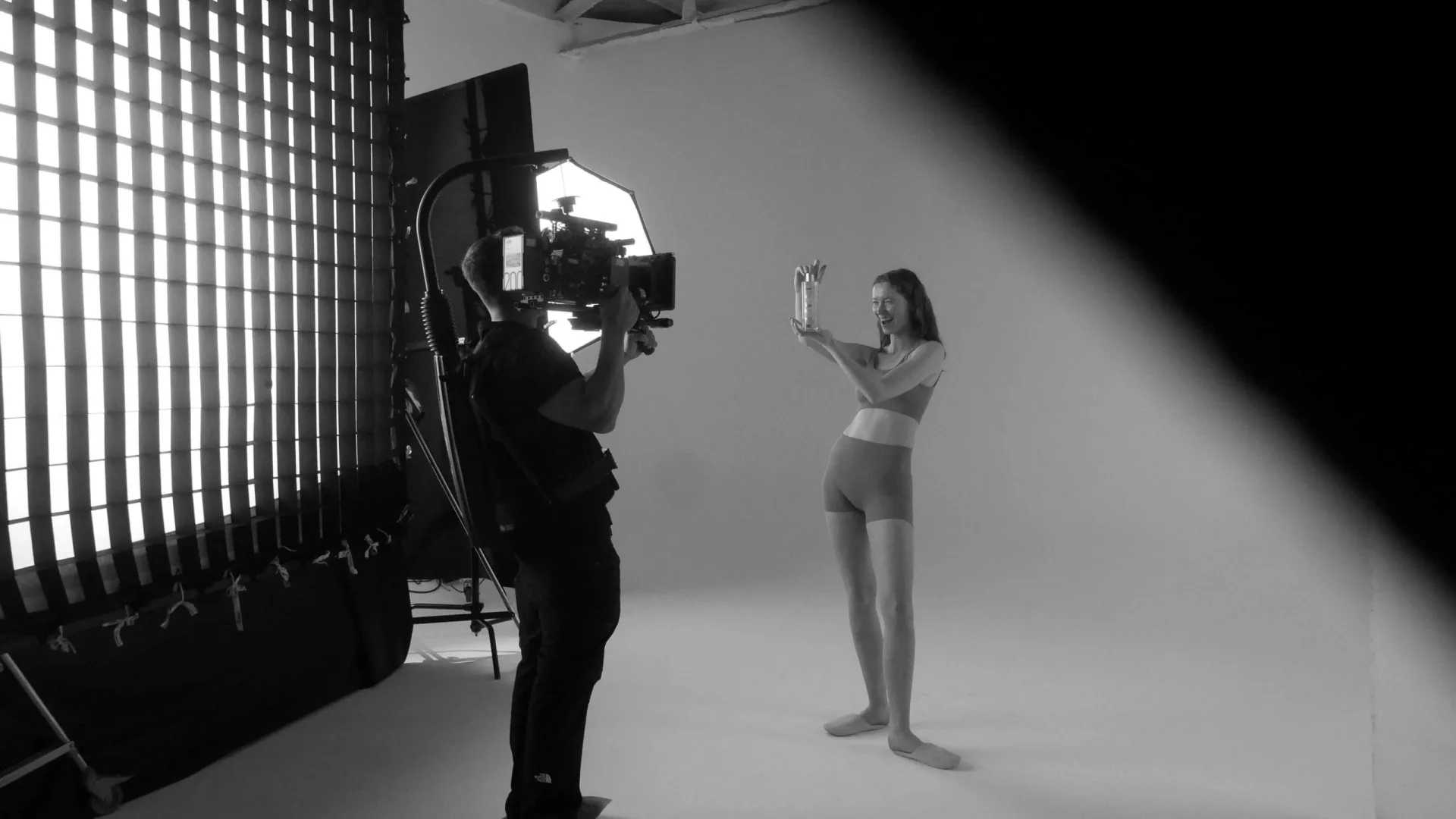 Isdin Ureadin shoot: camera operator filming a model holding up a product in the white studio