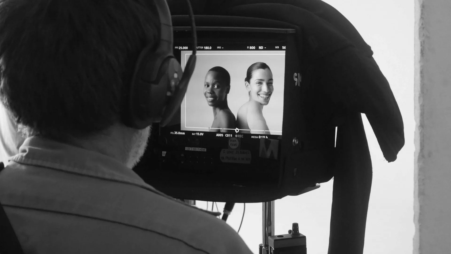 Isdin Ureadin shoot: crew member with headphones watching two smiling models on the monitor