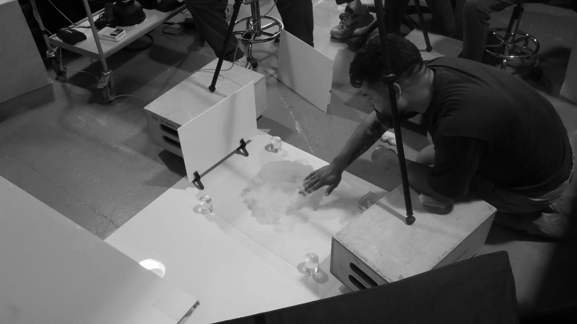 Isdin Ureadin shoot: crew member preparing a white tabletop set with small glass props
