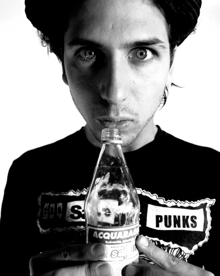 Black and white portrait from Jari's profile: a man holding a glass bottle to his lips
