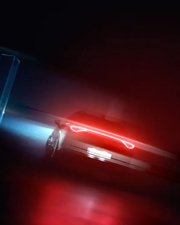 Frame from a commercial by Jari: a car's red tail light streaking through the dark