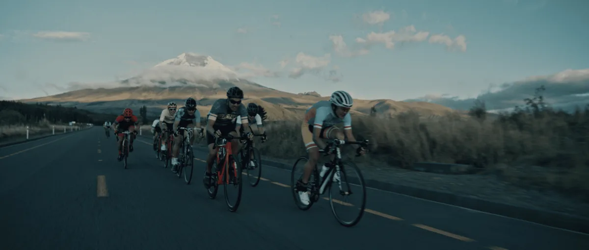 Ciclistas en carretera bajo un volcán nevado, de un anuncio de Juan Pablo Caballero