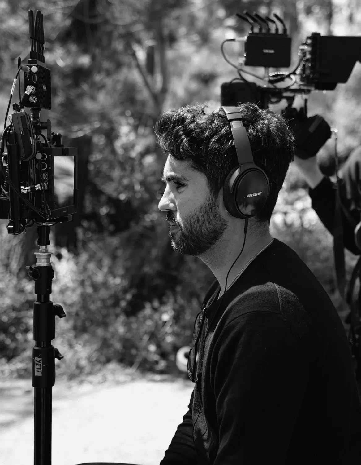 Man with headphones at a monitor on an outdoor shoot, from Miki Durán's work, in black and white