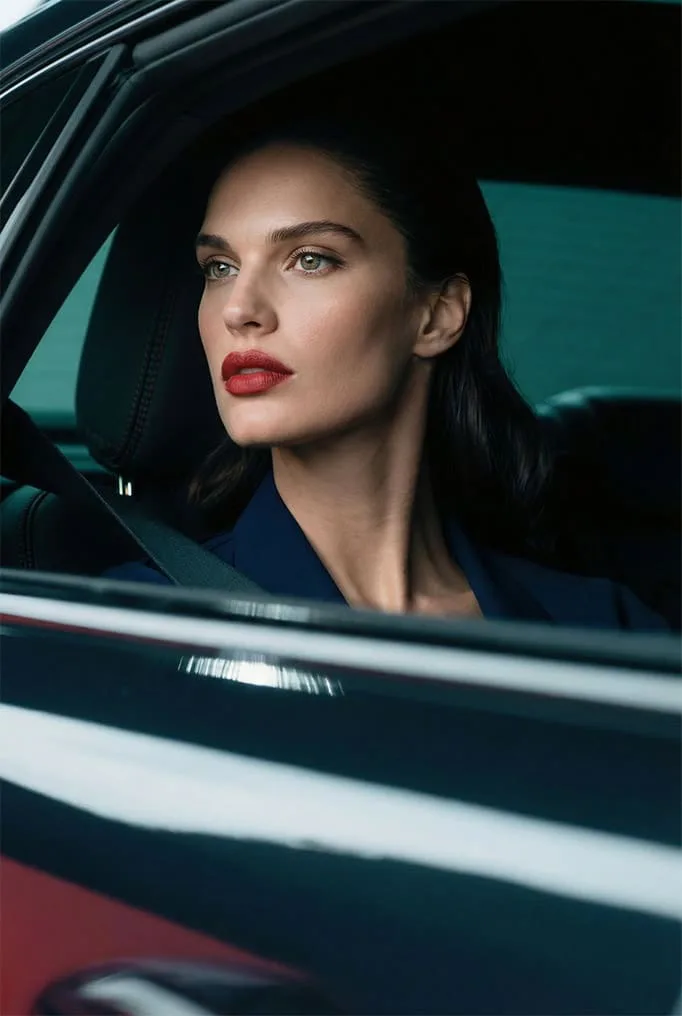 Mujer de labios rojos tras la ventanilla de un coche, trabajo con IA de Mister Nitch