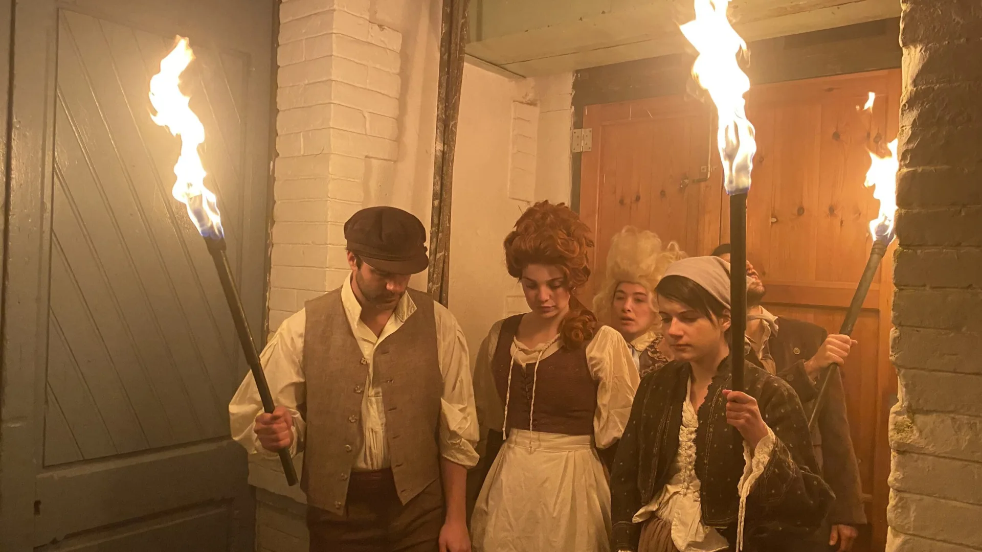 OCB Rolling Revolution shoot: actors in period costume holding torches in a corridor
