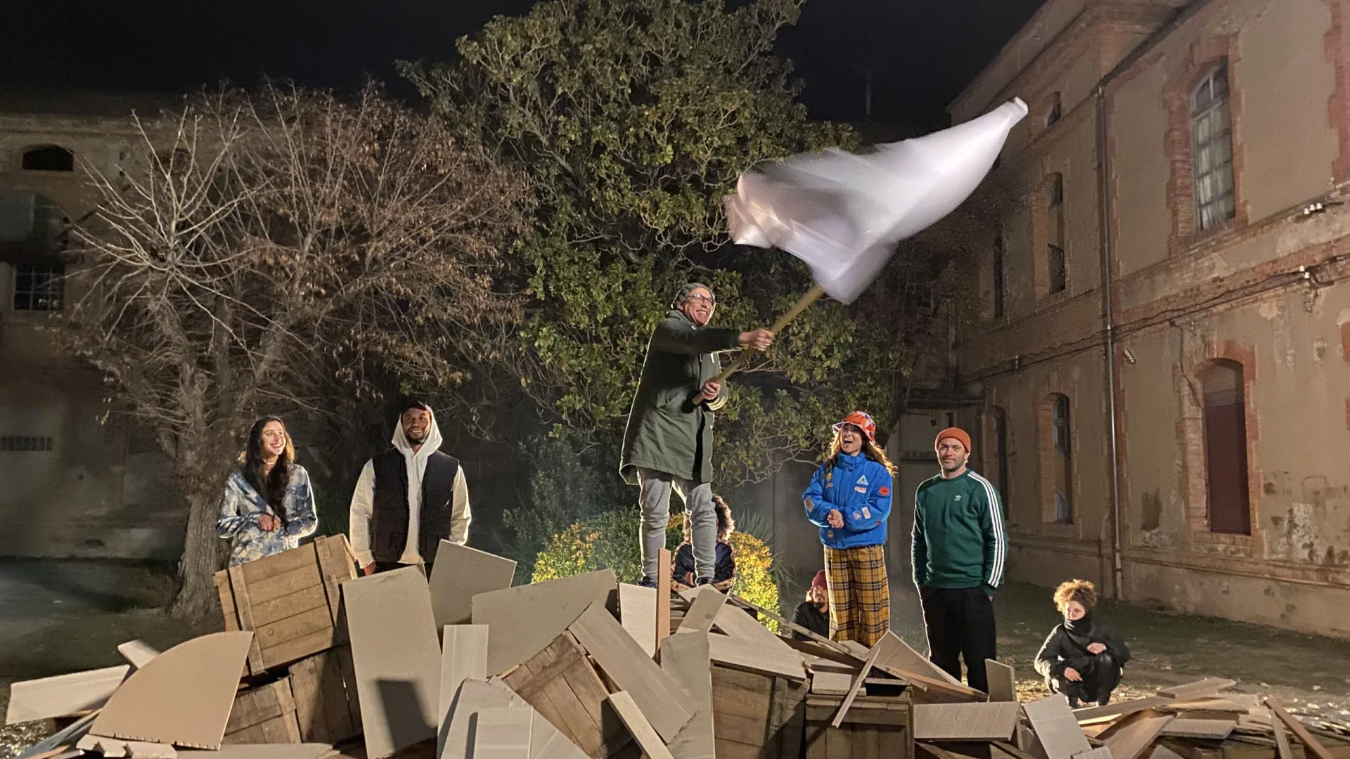 OCB Rolling Revolution shoot: actor waving a white flag on stacked crates at night
