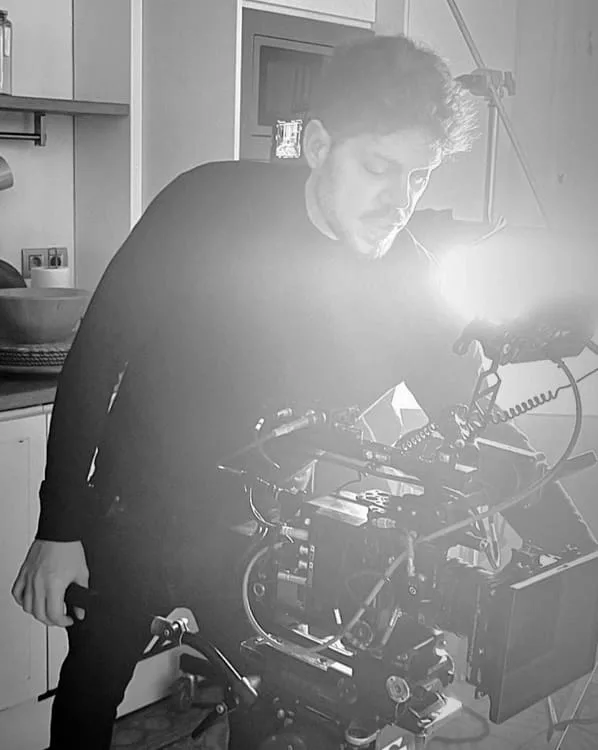 Black and white on-set photo from Pedro Abreu's profile: a man working a cinema camera