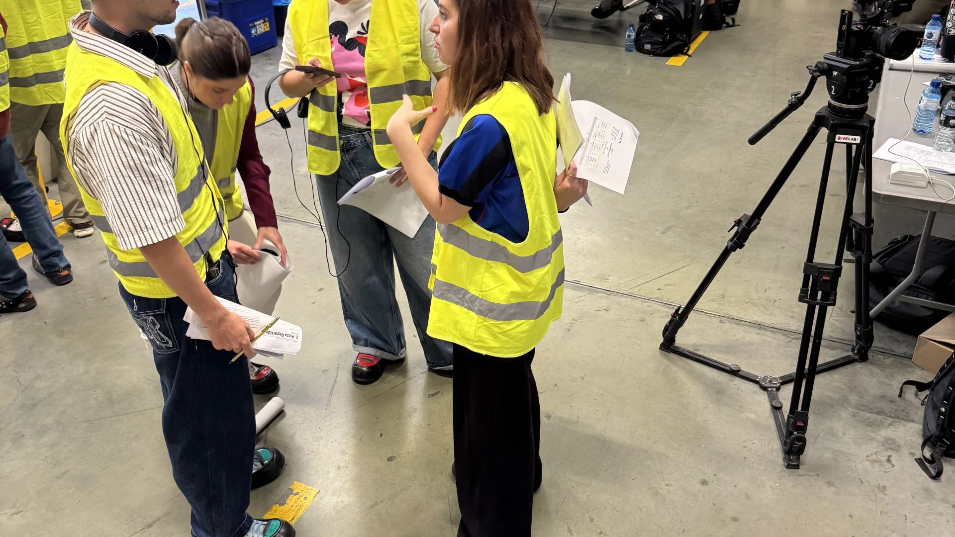 Pepsi x Nil Ojeda shoot: crew in hi-vis vests reviewing the script on the warehouse floor