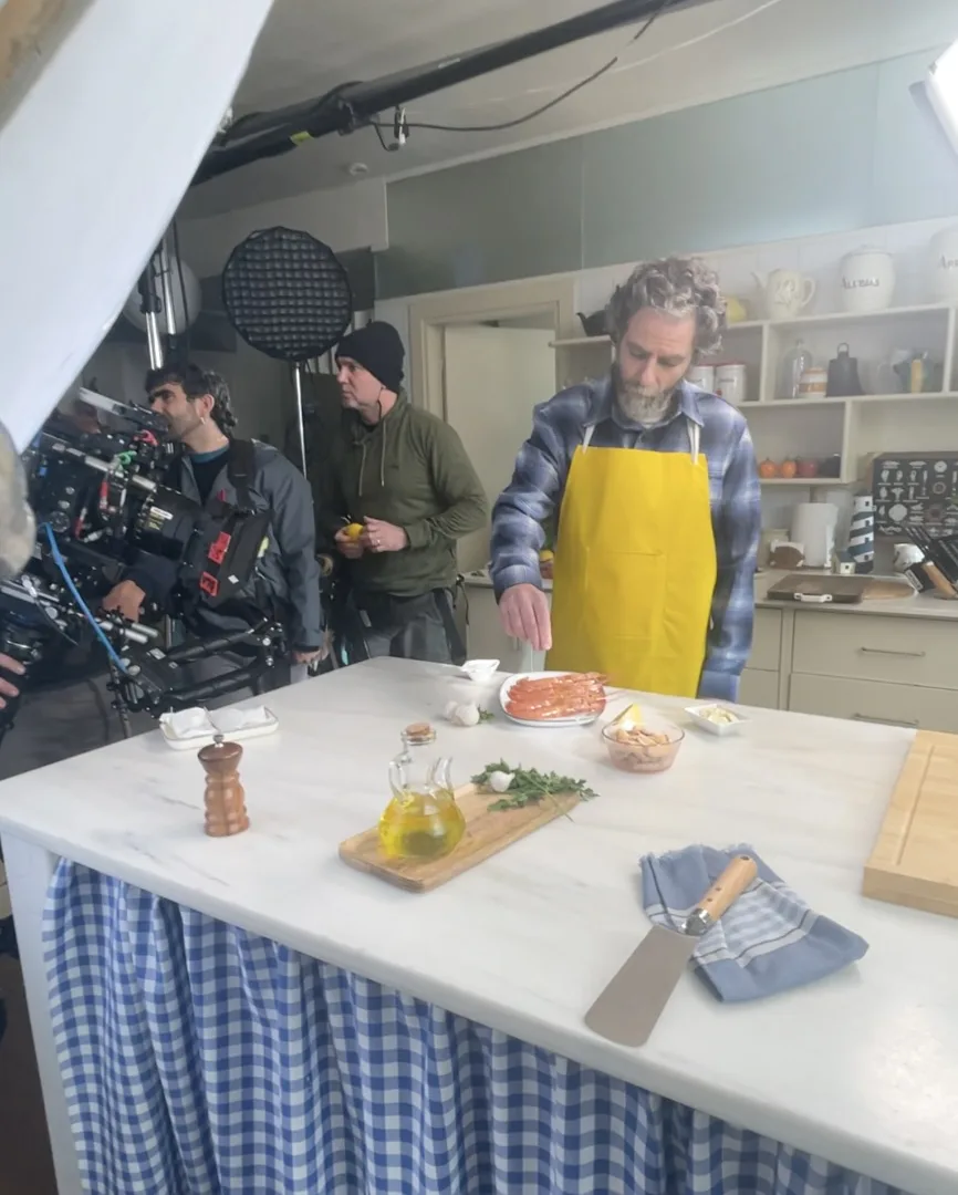 Pescanova shoot: actor in a yellow apron cooking prawns on a kitchen set, crew beside him
