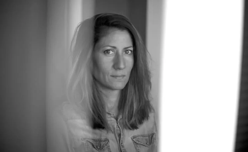 Retrato en blanco y negro de la directora Rebeca Calle junto a una ventana luminosa