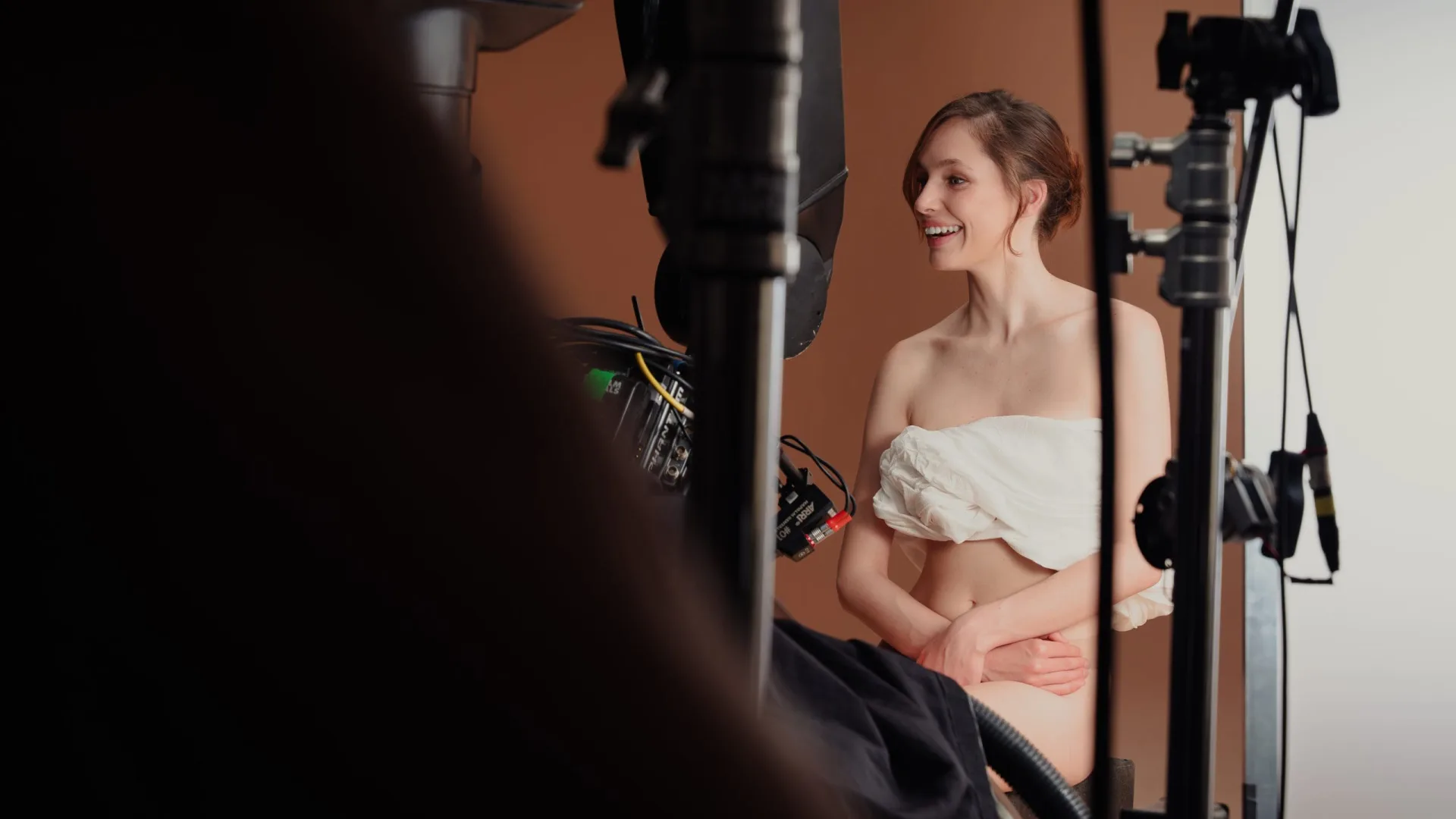 Sanex UAP shoot: smiling model wrapped in white fabric between light stands