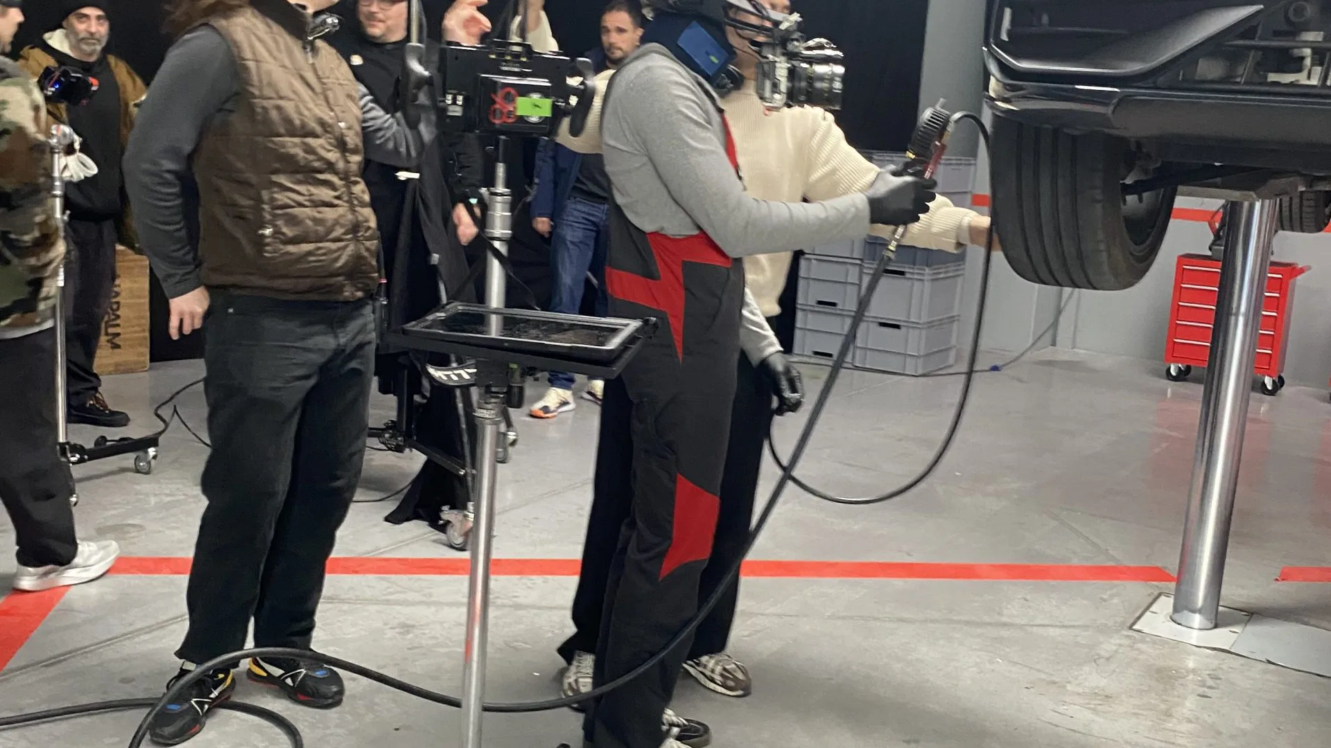 Seat Connect shoot: actor in mechanic overalls wearing a helmet camera rig under a raised car
