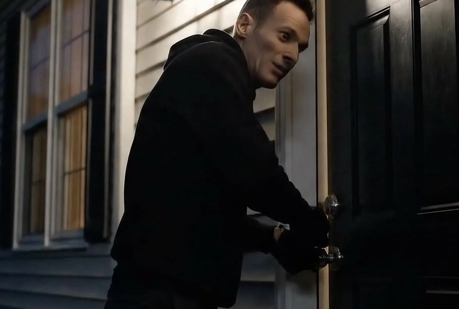 The death of visual evidence, AI frame: hooded man forcing a front door at night