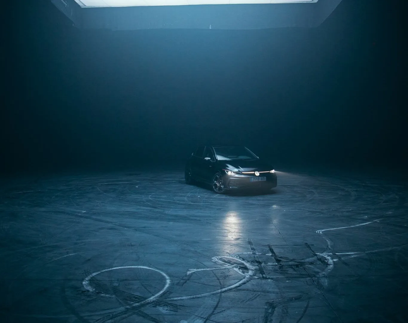 Volkswagen Golf GTI under a giant overhead light, drift marks covering the studio floor