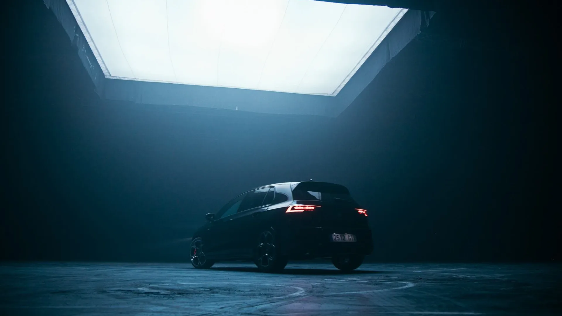 Volkswagen Golf GTI from behind, tail lights on, under a large studio softbox