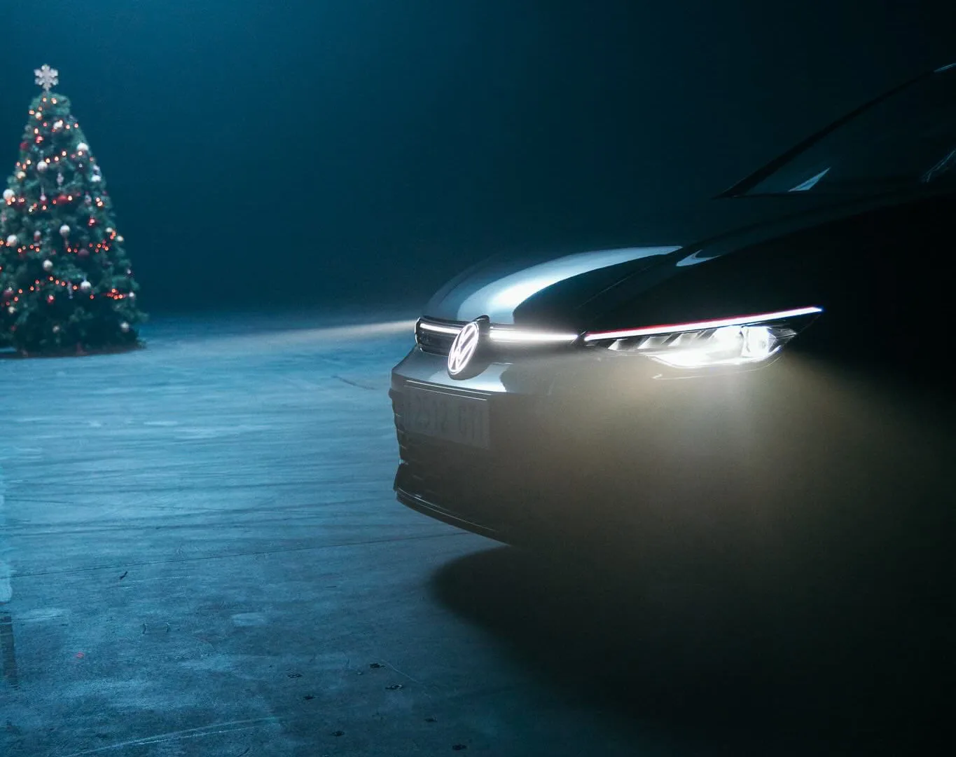 Volkswagen Golf GTI front with lit headlights and a Christmas tree in the misty studio