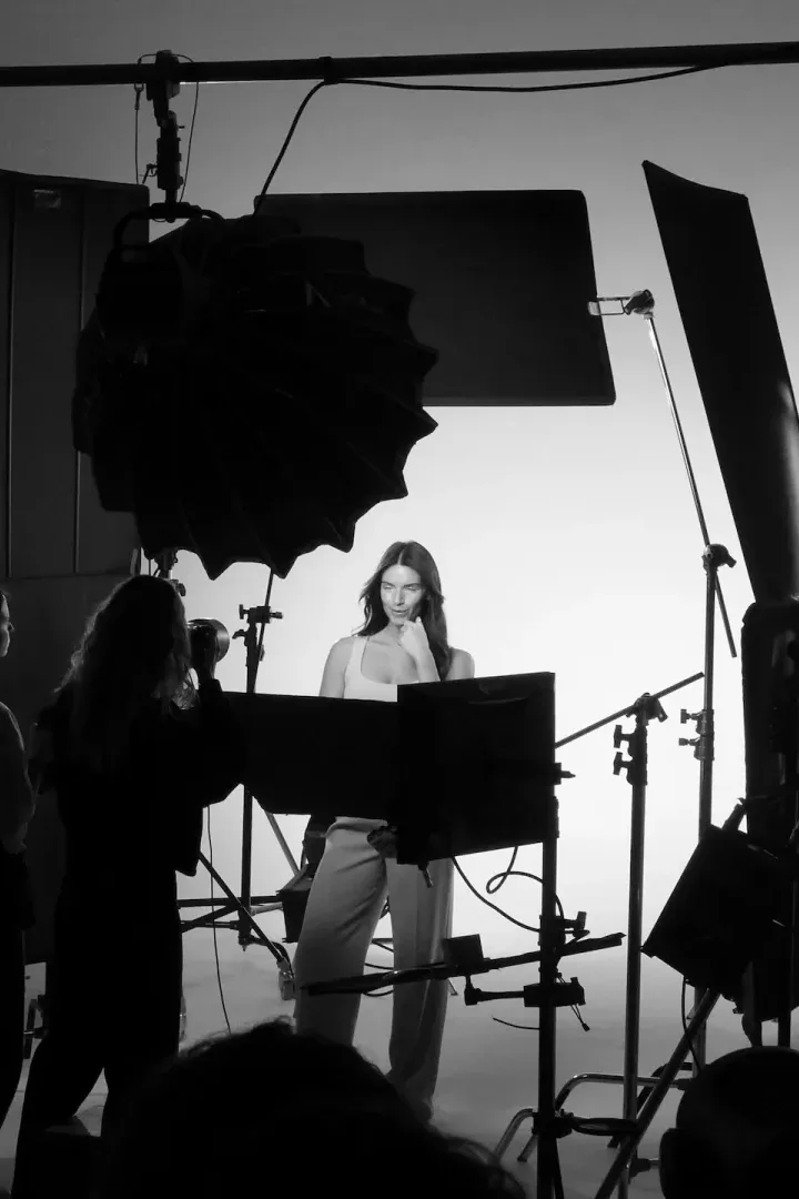 Rodaje en estudio en blanco y negro: el equipo de Glassy Films, a contraluz entre focos y banderas, rueda a una modelo ante un ciclorama blanco