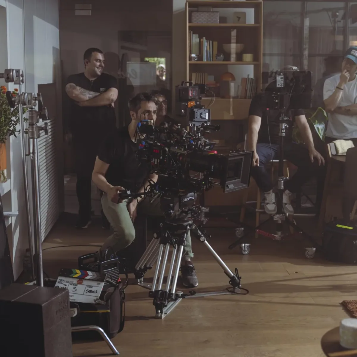 El equipo de rodaje de Glassy Films en el set: un operador prepara un plano en un salón mientras el equipo mira