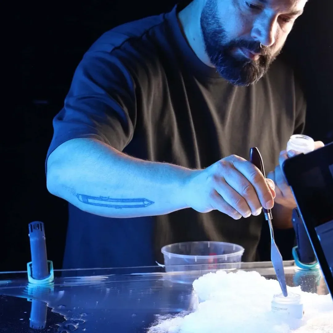 Making of de un rodaje de tabletop: un miembro del equipo trabaja en un montaje con hielo en una cubeta transparente bajo luz azul