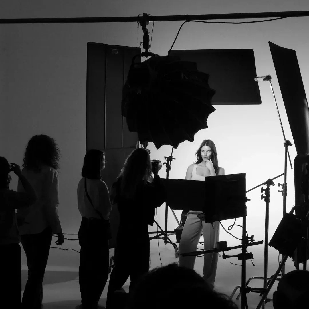 ISDIN Hyaluronic, making of: el equipo mira a la modelo posar bajo los focos del plató, en blanco y negro