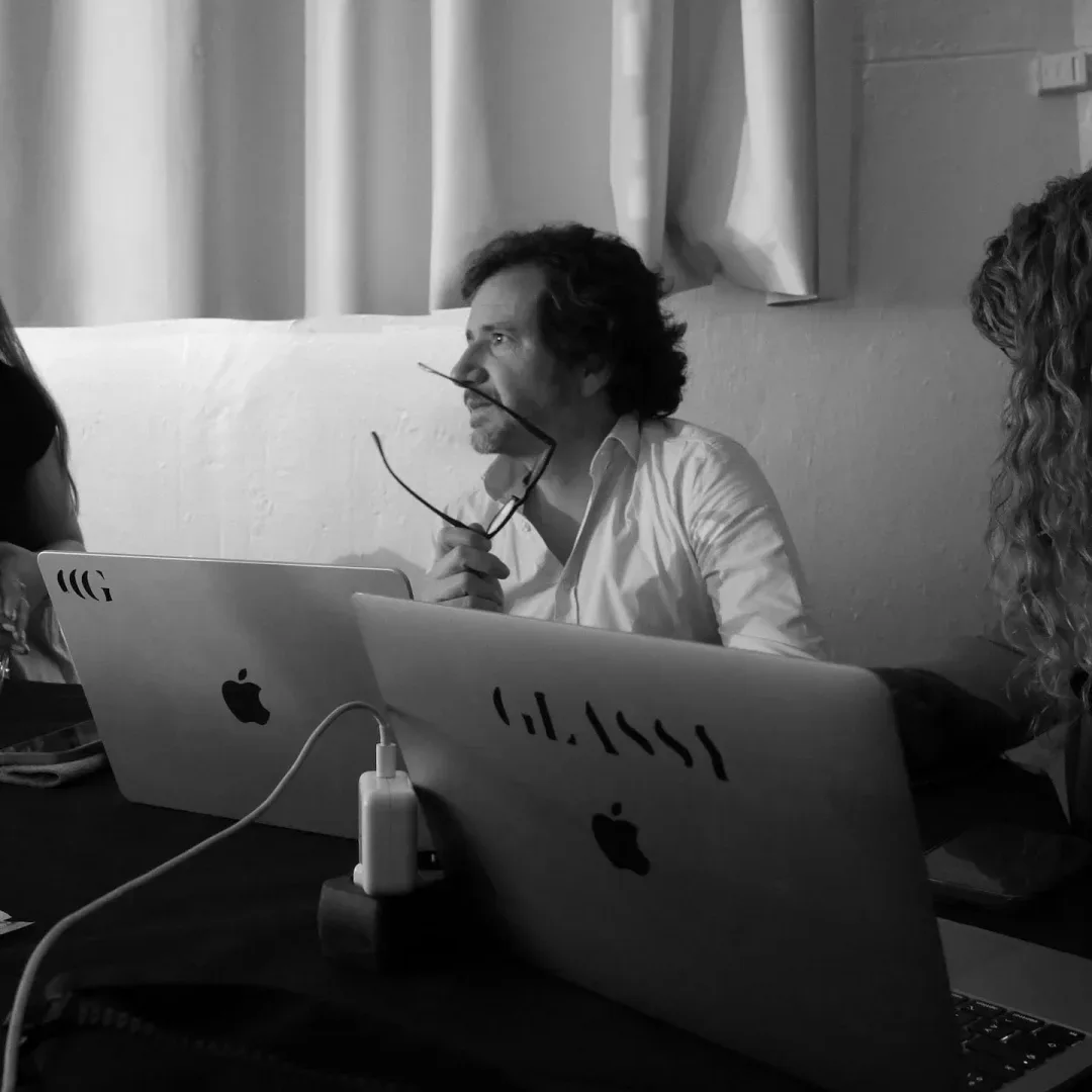 ISDIN Hyaluronic, making of: el equipo en una mesa con portátiles, uno con una pegatina de Glassy, en blanco y negro
