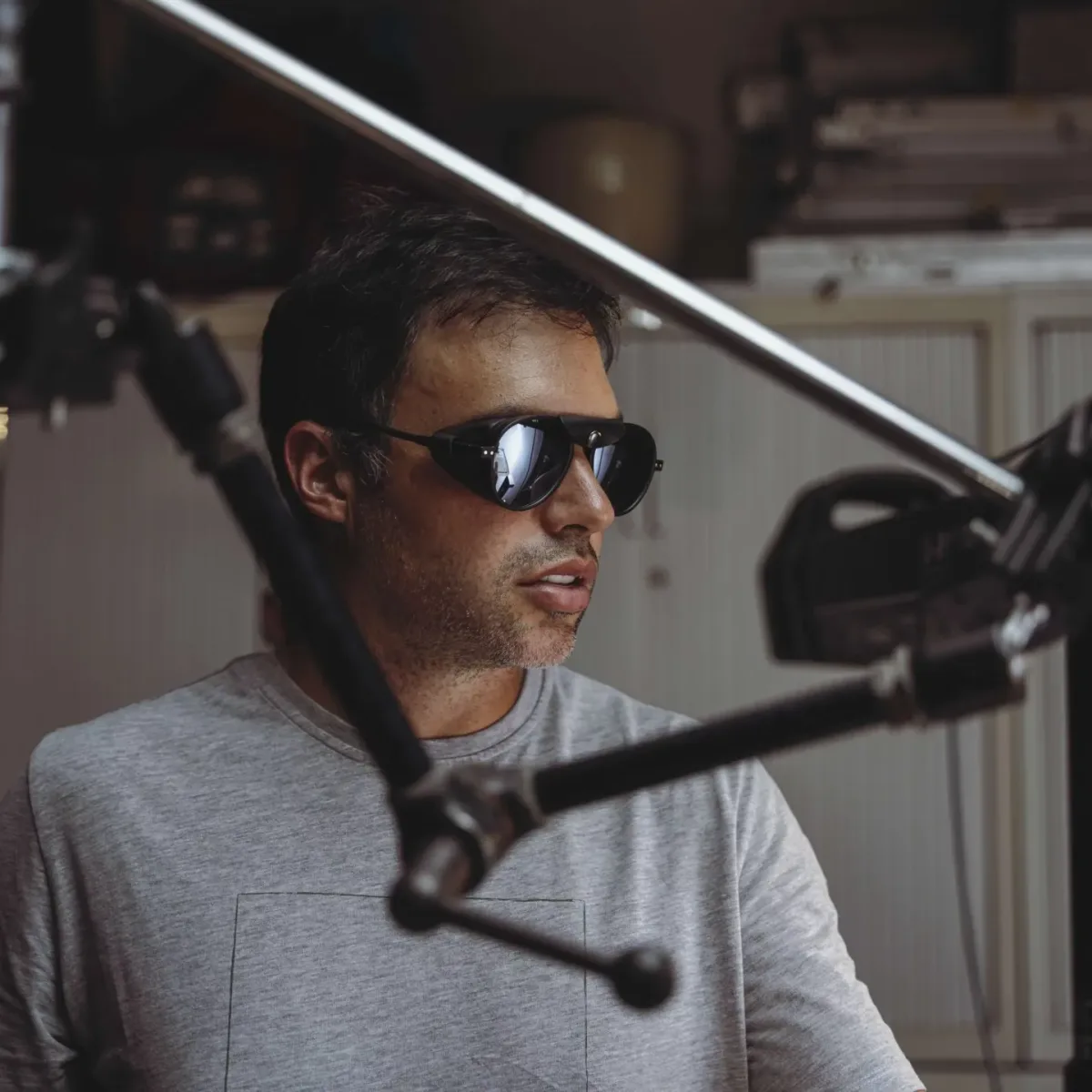 Un miembro del equipo de Glassy Films con gafas de sol entre los pies de foco del set